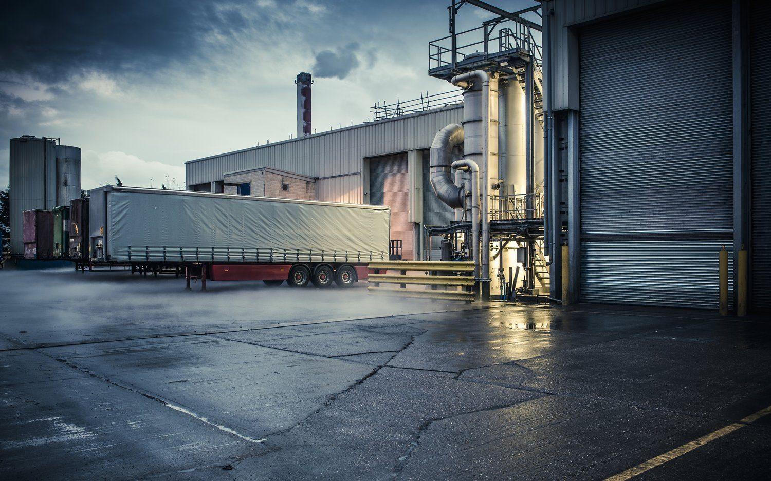 Ciężarówka z naczepą firankową czeka przy rampie zakładu produkcyjnego
